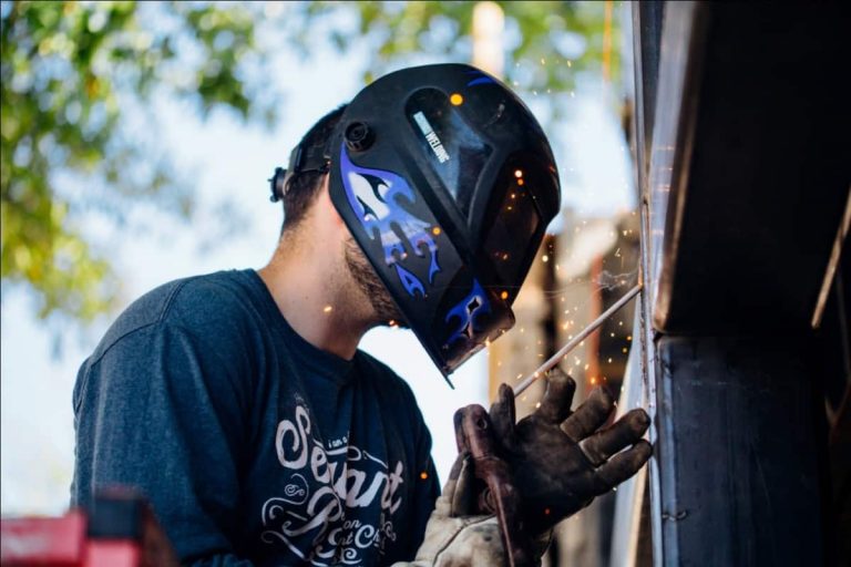 A man welding wearing gloves and an auto-darkening welding helmet